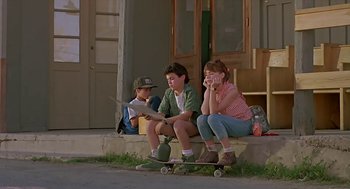 Movie still from “The Wizard” (1989), directed by Todd Holland – A group of people sitting on a porch with skateboards; Wide shot, Low angle