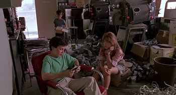 Movie still from “The Wizard” (1989), directed by Todd Holland – A boy and a girl sitting in a chair looking at their phones; Wide shot, High angle