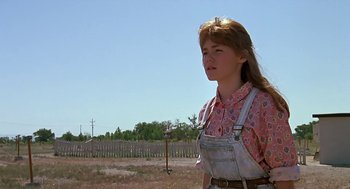 Movie still from “The Wizard” (1989), directed by Todd Holland – A woman standing in a field with a fence in the background; Medium shot, Low angle