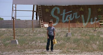 Movie still from “The Wizard” (1989), directed by Todd Holland – A young man holding a bag in a field; Wide shot, Low angle