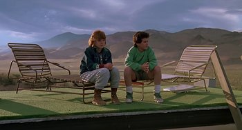 Movie still from “The Wizard” (1989), directed by Todd Holland – A couple of people sitting on top of a chair; Wide shot, Low angle