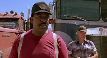 Movie still from “The Wizard” (1989), directed by Todd Holland – A man wearing a baseball cap standing in front of a truck; Medium shot, Low angle