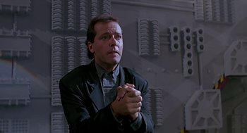 Movie still from “The Wizard” (1989), directed by Todd Holland – A man in a suit and tie holding his hands in a gesture; Medium shot, Low angle
