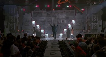 Movie still from “The Wizard” (1989), directed by Todd Holland – A man standing in front of an audience on a stage; Extreme Wide shot, Low angle