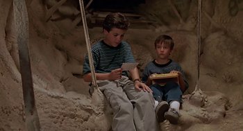 Movie still from “The Wizard” (1989), directed by Todd Holland – Two young boys sitting on a swing in a cave; Medium shot, High angle
