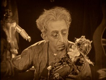Movie still from “The Wizard of Oz” (1925), directed by Larry Semon – An older man holding a puppet in his hands; Medium shot, Low angle