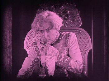 Movie still from “The Wizard of Oz” (1925), directed by Larry Semon – An old man sitting in a chair with his hand under his chin; Medium shot, High angle