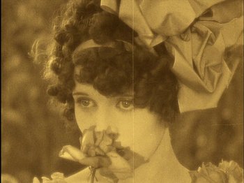 Movie still from “The Wizard of Oz” (1925), directed by Larry Semon – An old photo of a woman holding a rose; Extreme Close Up shot, High angle
