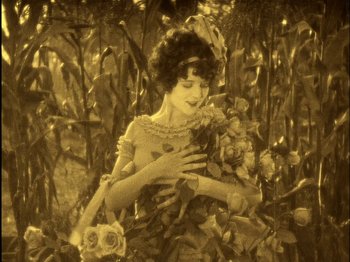 Movie still from “The Wizard of Oz” (1925), directed by Larry Semon – An old photo of a woman holding a bunch of roses; Medium shot, High angle