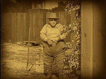 Movie still from “The Wizard of Oz” (1925), directed by Larry Semon – An old photo of a man standing in the dirt; Wide shot, High angle