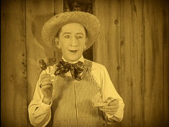 Movie still from “The Wizard of Oz” (1925), directed by Larry Semon – An old man wearing a straw hat and holding a fork; Medium shot, High angle