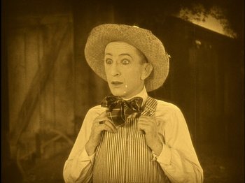 Movie still from “The Wizard of Oz” (1925), directed by Larry Semon – An old photo of a man holding a bow tie; Close Up shot, High angle