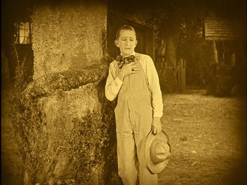 Movie still from “The Wizard of Oz” (1925), directed by Larry Semon – An old photo of a young man in a hat and bow tie; Medium shot, High angle
