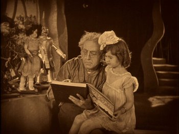 Movie still from “The Wizard of Oz” (1925), directed by Larry Semon – An old man and a little girl are reading a book; Medium shot, High angle