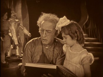 Movie still from “The Wizard of Oz” (1925), directed by Larry Semon – An old man and a little girl looking at a book; Medium shot, High angle