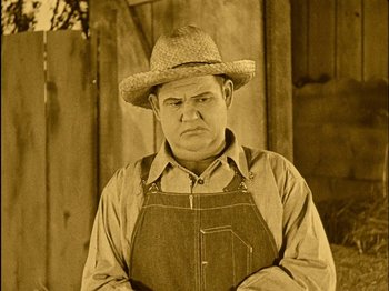 Movie still from “The Wizard of Oz” (1925), directed by Larry Semon – A man wearing an overalls and a straw hat; Medium shot, High angle