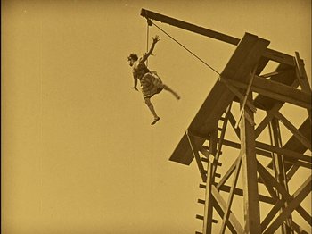 Movie still from “The Wizard of Oz” (1925), directed by Larry Semon – A man hanging from a rope on top of a wooden structure; Wide shot, Low angle