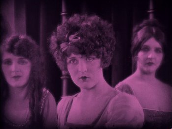 Movie still from “The Wizard of Oz” (1925), directed by Larry Semon – A woman with a bow in her hair and two other women in the background; Close Up shot, High angle