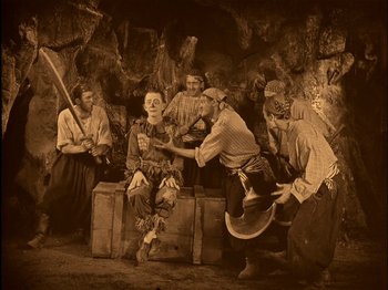Movie still from “The Wizard of Oz” (1925), directed by Larry Semon – A group of people dressed in costumes in a cave; Wide shot, High angle