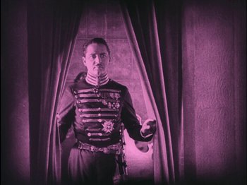 Movie still from “The Wizard of Oz” (1925), directed by Larry Semon – A man in a military uniform standing in front of a curtain; Medium shot, Low angle