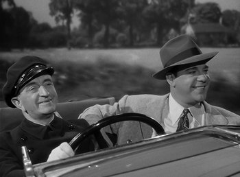 Movie still from “The Wolf Man” (1941), directed by George Waggner – A couple of men sitting in the back seat of a car; Medium shot, High angle