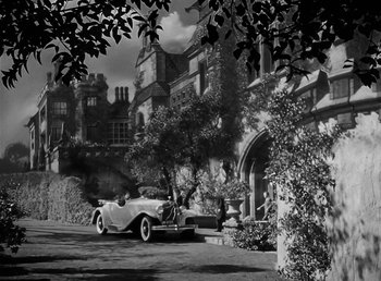 Movie still from “The Wolf Man” (1941), directed by George Waggner – An old car parked in front of a house; Extreme Wide shot, High angle