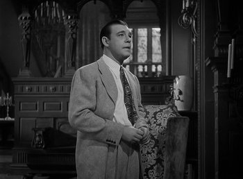 Movie still from “The Wolf Man” (1941), directed by George Waggner – A black and white photo of a man in a suit and tie; Medium shot, Low angle