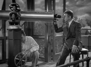 Movie still from “The Wolf Man” (1941), directed by George Waggner – A man in a suit and tie holding a camera and a man in a suit and tie holding a camera; Medium shot, High angle