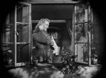 Movie still from “The Wolf Man” (1941), directed by George Waggner – A black and white photo of a woman looking out of a window; Medium shot, Low angle
