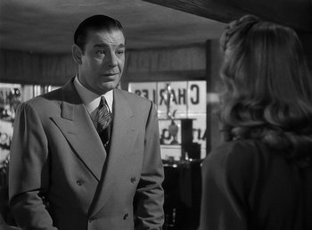 Movie still from “The Wolf Man” (1941), directed by George Waggner – A man wearing a suit and tie talking to a woman; Medium shot, Over the shoulder angle