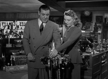 Movie still from “The Wolf Man” (1941), directed by George Waggner – A man and a woman are looking at wine bottles; Medium shot, Low angle