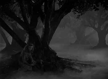 Movie still from “The Wolf Man” (1941), directed by George Waggner – A man sitting on the ground next to a large tree; Wide shot, High angle