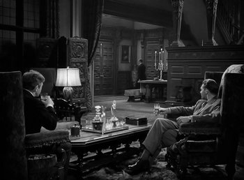 Movie still from “The Wolf Man” (1941), directed by George Waggner – A man sitting on a couch in a living room; Wide shot, High angle