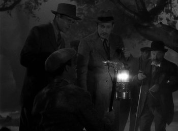 Movie still from “The Wolf Man” (1941), directed by George Waggner – A group of men standing next to each other holding a lamp; Medium shot, High angle