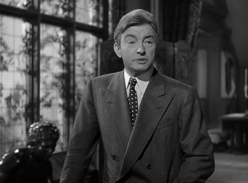 Movie still from “The Wolf Man” (1941), directed by George Waggner – A man wearing a suit and tie standing in front of a window; Close Up shot, Over the shoulder angle