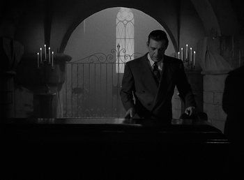 Movie still from “The Wolf Man” (1941), directed by George Waggner – A man standing in front of a table in a church; Wide shot, Low angle