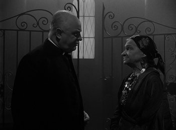 Movie still from “The Wolf Man” (1941), directed by George Waggner – An older man and a younger woman standing next to each other in front of a door; Medium shot, Over the shoulder angle