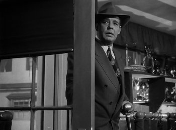 Movie still from “The Wolf Man” (1941), directed by George Waggner – A black and white photo of a man in a suit and hat; Medium shot, Low angle