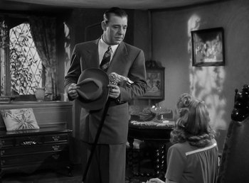 Movie still from “The Wolf Man” (1941), directed by George Waggner – A man in a suit and a hat in a living room; Medium shot, Low angle
