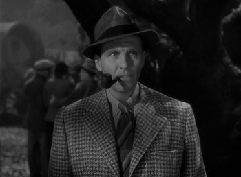 Movie still from “The Wolf Man” (1941), directed by George Waggner – A black and white photo of a man smoking a pipe; Close Up shot, High angle