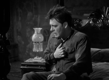 Movie still from “The Wolf Man” (1941), directed by George Waggner – A black and white photo of a man sitting on a chair; Medium shot, Low angle