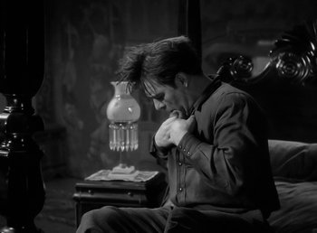 Movie still from “The Wolf Man” (1941), directed by George Waggner – A man sitting on a chair in a dark room; Medium shot, Over the shoulder angle