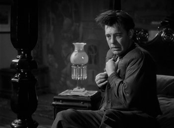 Movie still from “The Wolf Man” (1941), directed by George Waggner – A black and white photo of a man sitting in a chair; Medium shot, Low angle