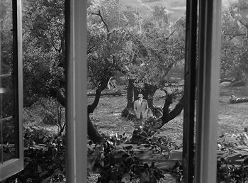 Movie still from “The Wolf Man” (1941), directed by George Waggner – A man standing in front of a window with trees in the background; Extreme Wide shot, Over the shoulder angle