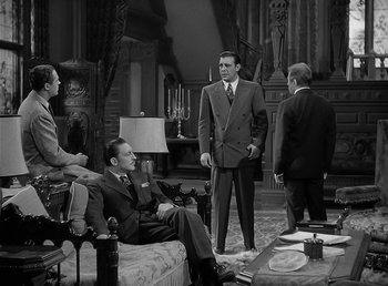 Movie still from “The Wolf Man” (1941), directed by George Waggner – A group of people in a living room talking to each other; Wide shot, High angle