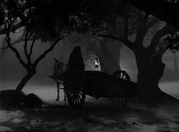 Movie still from “The Wolf Man” (1941), directed by George Waggner – A man riding a horse drawn carriage through the woods; Wide shot, High angle