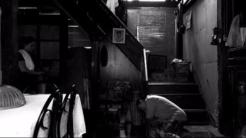 A man kneeling down next to stairs in a room