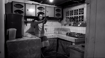 A man holding a gun inside of a kitchen
