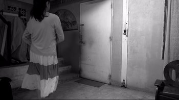 Movie still from “The Woman Who Left” (2016), directed by Lav Diaz – A woman is walking in front of an open door; Wide shot, Low angle