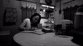A woman sitting at a table writing on a piece of paper